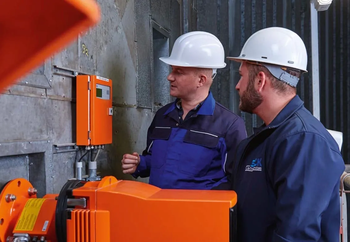 Two EMS service engineers in hard hats working on an analyser